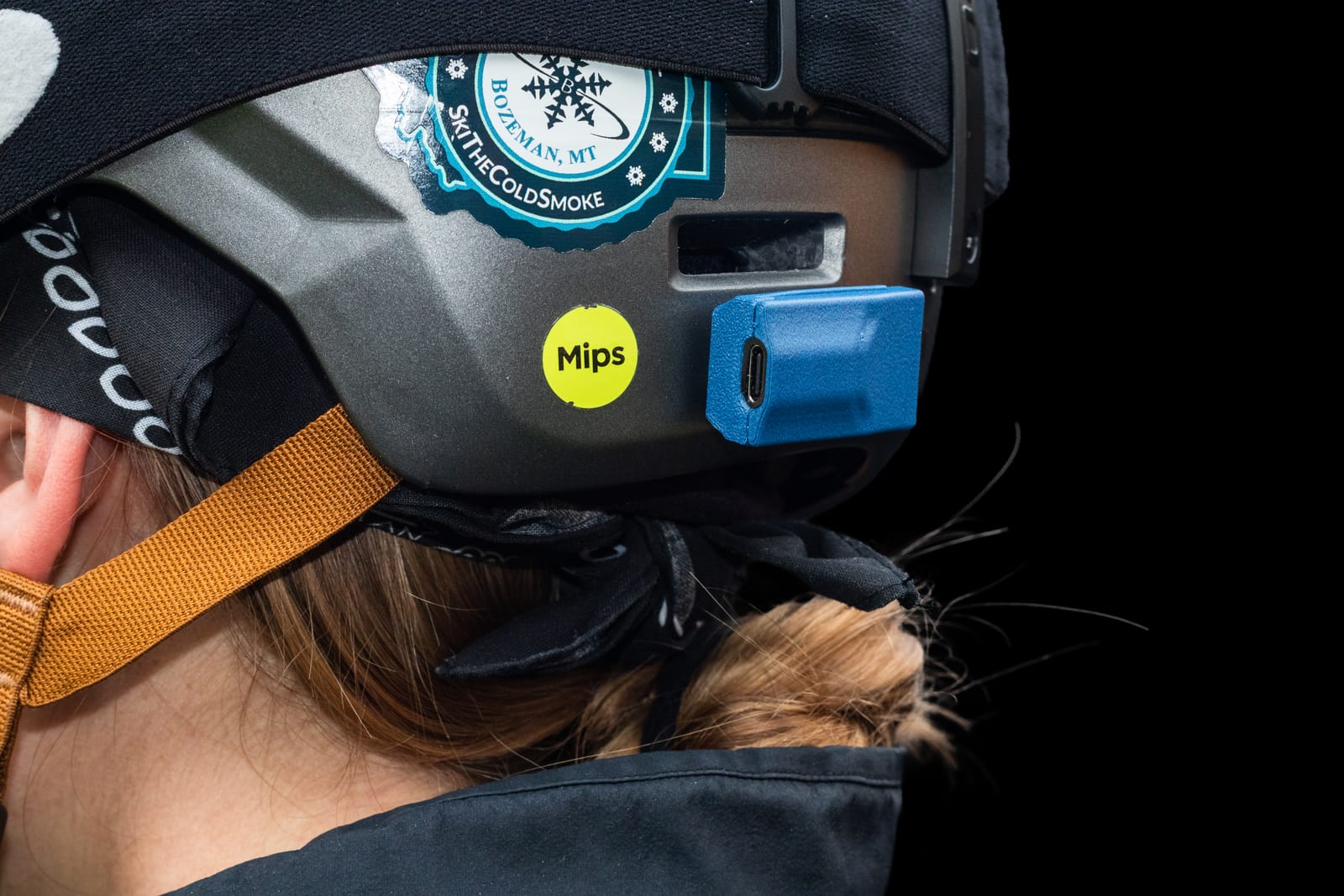 A blue Noggin sensor mounted on the back of a skier's helmet